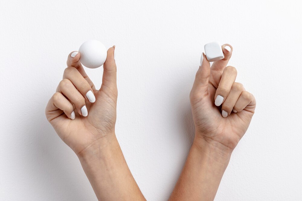 Front view of hands holding small cube and ball
